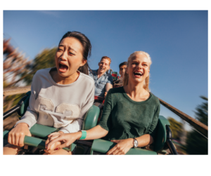 Two women enjoying a rollercoaster ride, symbolizing the emotional ups and downs of midlife