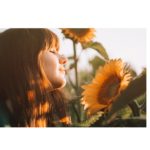 Woman basking in the sunlight while admiring a sunflower, symbolizing natural Vitamin D absorption, as featured in 'The Sunshine Vitamin: 20 Ways to Boost Your D Levels Naturally'.