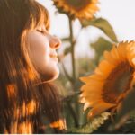Woman basking in the sunlight while admiring a sunflower, symbolizing natural Vitamin D absorption, as featured in 'The Sunshine Vitamin: 20 Ways to Boost Your D Levels Naturally'.