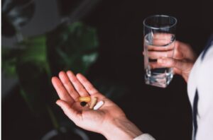 Woman holding Vitamin D supplements, a practical way to increase intake as discussed in the article 'The Sunshine Vitamin: 20 Ways to Boost Your D Levels Naturally'.