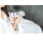 Hydration in Focus: A woman holds a clear glass filled with fresh water, a reflection of her commitment to one of the most essential health hacks—staying hydrated for optimal well-being