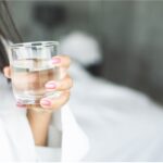 Hydration in Focus: A woman holds a clear glass filled with fresh water, a reflection of her commitment to one of the most essential health hacks—staying hydrated for optimal well-being. 44 Simple Health Hacks.