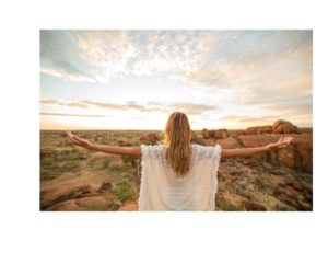 A woman stands with her arms open wide, embracing the sunrise. She is silhouetted against the vibrant hues of the early morning sky, symbolizing openness, renewal, and the welcoming of new beginnings through mindfulness. The Power of Mindfulness. 