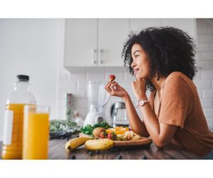 a busy women stopping for. break to eat healthy food in her kitchen.