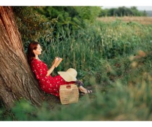 A woman seated outdoors, leaning against a tree while writing in her journal, embodying the introspective conclusion and personal reflection on the transformative journey to happiness. Simple Habits for Happiness. 