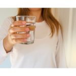 Image of a woman holding a glass of water, illustrating hydration as an important aspect of the Anti-Inflammatory Diet.