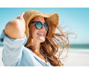 A Woman at the beach smiling loving her life. 