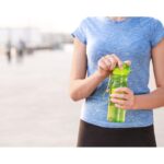 A woman holding a water container, emphasizing the importance of staying hydrated while traveling.