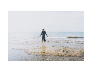 A woman walking along the beach, representing relaxation and the calming effects of frequency therapy for emotional balance.