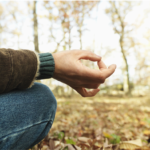 A man sits peacefully on the forest floor, meditating in a serene, natural setting to enhance mindfulness and mental well-being.