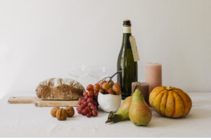 A rustic arrangement of fall foods featuring pears, grapes, freshly baked bread, and cider, alongside a bowl of quince, embodying the richness of the autumn harvest.