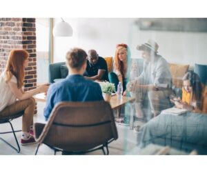 A diverse group of creative professionals engaged in a brainstorming session in a modern, well-lit office, demonstrating teamwork and emotional intelligence