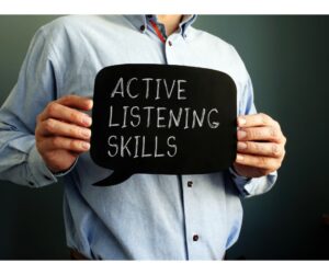 A man holding a blackboard sign that says 'Active Listening Skills', representing a key aspect of emotional intelligence.