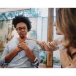  comforting scene where a Caucasian woman reassures a distressed African American woman in a peaceful indoor setting, highlighting empathy and emotional intelligence.