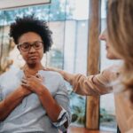 comforting scene where a Caucasian woman reassures a distressed African American woman in a peaceful indoor setting, highlighting empathy and mastering emotional intelligence.
